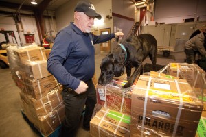 Dog-handler Mark Hicks leading a black Labrador retriever named OD (short for Over Dose) through his paces, sniffing luggage and freight for drugs and alcohol before the cargo flight heads north. (Bill Braden photo).