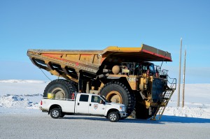 A Scarlet Security pick-up truck is dwarfed by a huge off-road hauler on Canada's ice highway.